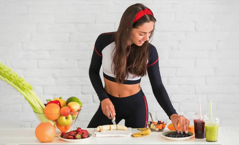 Mujer preparando comida saludable con frutas y batidos para prevenir enfermedades.